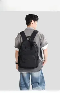 Rear view of a black lightweight nylon backpack with multiple zipper pockets on model