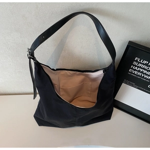 Detail view of large black tote bag featuring pink lining and interior pocket