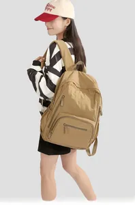 Detail of a khaki nylon outdoor backpack showing multiple functional zipper pockets
