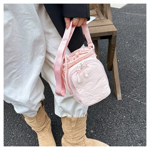 Detail of pink nylon crossbody bag showing the drawstring closure and zipper pocket