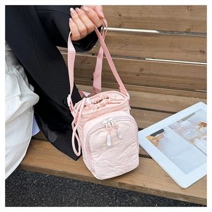 Detailed shot of light pink drawstring crossbody bag with front zipper pocket and nylon texture