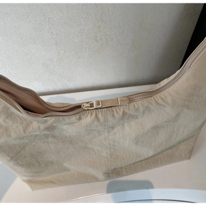 Detail of smooth zipper closure on beige nylon tote with pleated texture fabric