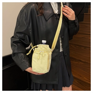 Detail of yellow nylon crossbody water bottle bag with front zipper pocket and strap