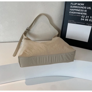 Close-up of khaki nylon hobo bag on a minimalist display stand with adjustable strap