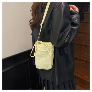 Detail of yellow nylon crossbody water bottle bag with adjustable strap and dual pockets