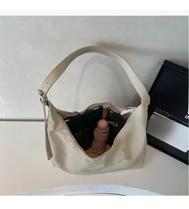 Detail showing large capacity of the beige hobo bag holding a tablet and umbrella