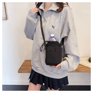 Detail of black nylon crossbody water bottle bag with adjustable strap on a wooden bench