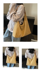 Detail of a large yellow nylon tote bag featuring an adjustable leather strap on model