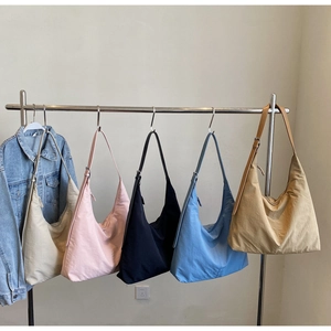Detailed view of large nylon tote bags in five different colors with adjustable shoulder straps