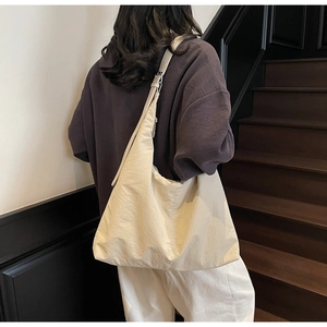 Close-up of the adjustable wide shoulder strap and metal buckle on this cream tote bag