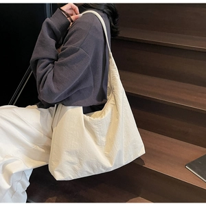 Side view of large cream hobo tote bag with pleated texture on a model in daily wear