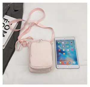 Pink nylon crossbody bag shown next to a tablet to demonstrate compact storage capacity