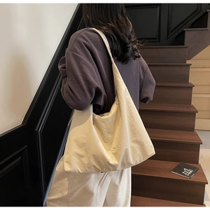 Close-up of a cream white minimalist oversized hobo tote bag with a soft wrinkled texture