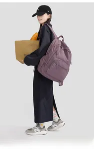 Detail of purple nylon backpack with multiple zipper pockets shown on casual model