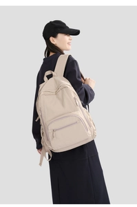Detail view of khaki nylon backpack featuring multiple front zippers and durable straps