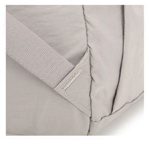 Macro view of reinforced stitching on a lightweight light gray nylon outdoor backpack