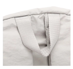 Close-up of durable light gray nylon fabric and reinforced stitching on backpack handle