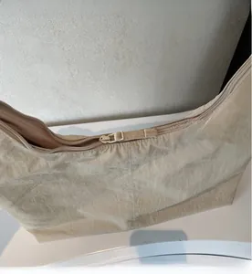 Close-up of smooth zipper closure on beige large capacity tote bag with textured nylon fabric