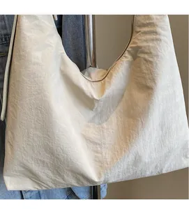 Detail showing the soft wrinkled nylon fabric and zipper of the cream white tote bag