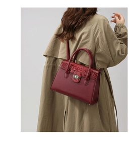 Burgunderfarbene Handtasche mit Krokoprägung, getragen zum khakifarbenen Trenchcoat