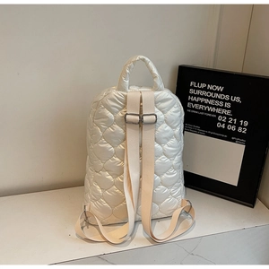 Detail of quilted heart embroidery on cream nylon backpack with metal adjustment buckles