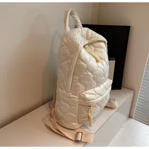 Detail of cream quilted puffer backpack featuring shiny nylon fabric and diamond stitching