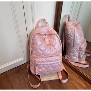 Detail of pink quilted puffer backpack with heart pattern and pearlescent finish