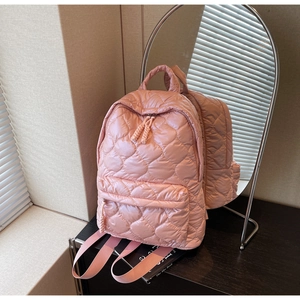 Macro shot of pink heart-quilted backpack with smooth zipper and durable top handle