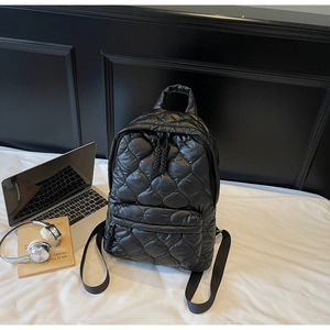 Close-up of black quilted puffer backpack featuring soft padded texture and zipper details