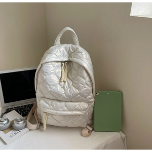 Detail of white quilted heart patterns on glossy nylon backpack with woven zipper pulls