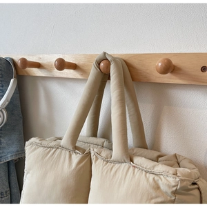 Detail of light khaki quilted nylon tote bag featuring soft padded texture and top handle