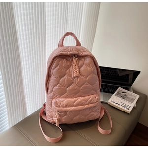 Close-up of pink quilted backpack featuring heart stitching and dual zipper detail