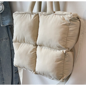 Close-up of quilted beige puff tote bag with soft padded handles and nylon texture