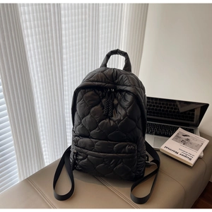 Macro detail of black quilted nylon backpack with rhombus stitching and front zipper pocket
