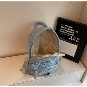 Detail view of the quilted light blue backpack showing interior compartment and zipper