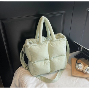 Detail view of mint green quilted puffer tote bag with thick handles and adjustable strap