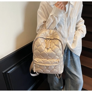 Close-up of champagne gold quilted backpack with metallic finish and embroidery detail