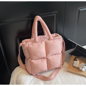 Close-up of pink quilted puffer tote bag with adjustable strap in a stylish bedroom setting