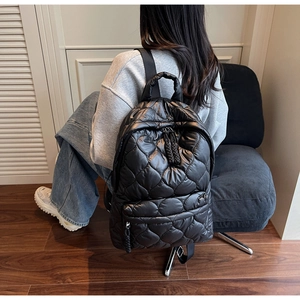 Macro shot of black quilted puffy backpack showing the textured nylon material and stitching