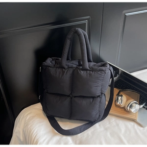 Close-up of black quilted puffer tote bag with stitched grid pattern and soft padded handle