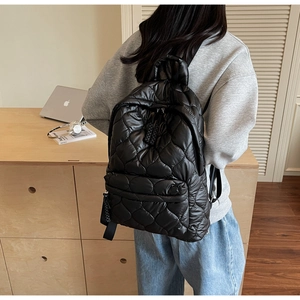 Detailed shot of a black quilted down fabric backpack with diamond stitching and zippers
