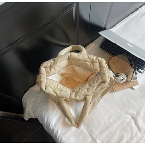 Close-up of beige quilted puffy tote bag with wide opening and large storage space