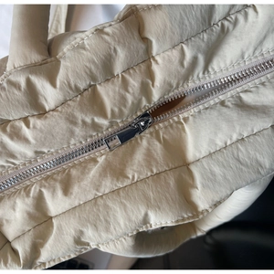Macro shot of silver metal zipper and soft quilted fabric texture on beige tote bag