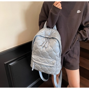 Close-up of quilted nylon backpack with thick braided rope zip pulls and diamond stitching