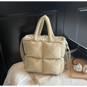 Macro detail of the creamy white quilted nylon puffer tote bag in a casual setting