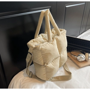 Detail of beige quilted puff tote bag with soft padded handles and wide shoulder strap