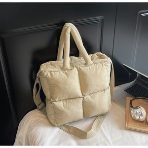Detailed macro view of beige quilted puffy tote bag with soft padded texture and handles