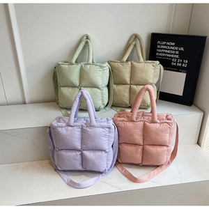 Close-up of quilted puffer bags in four pastel colors on a marble display stand