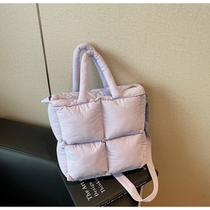 Close-up of lavender quilted puffer tote bag on black books in a minimalist setting