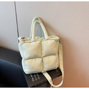 Detail of light green quilted puffer tote bag featuring soft nylon texture and padded handles